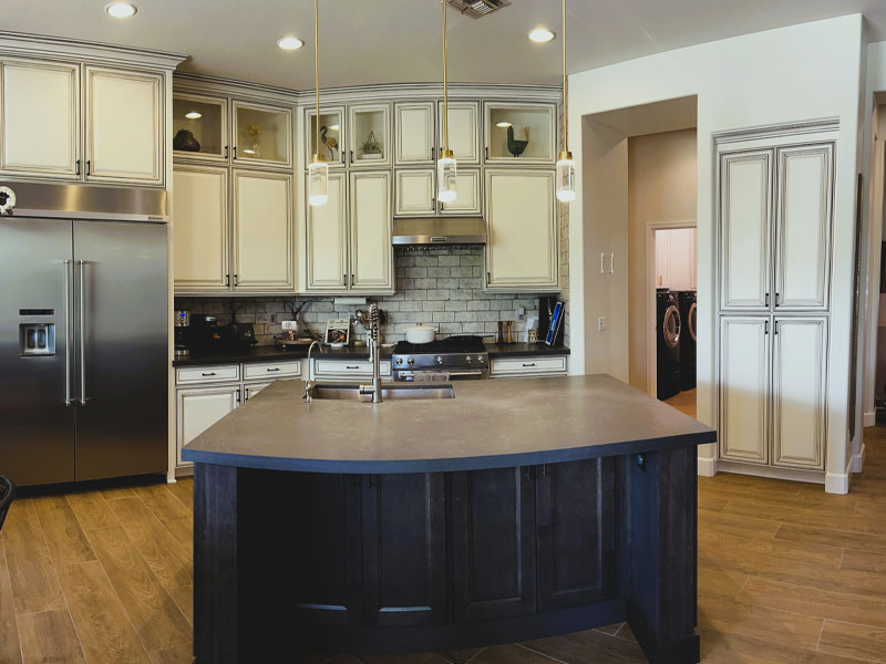 Modern kitchen with dark island, stainless steel appliances, and light cabinetry, showcasing quality craftsmanship relevant to restoration and reconstruction services in Anthem, AZ.