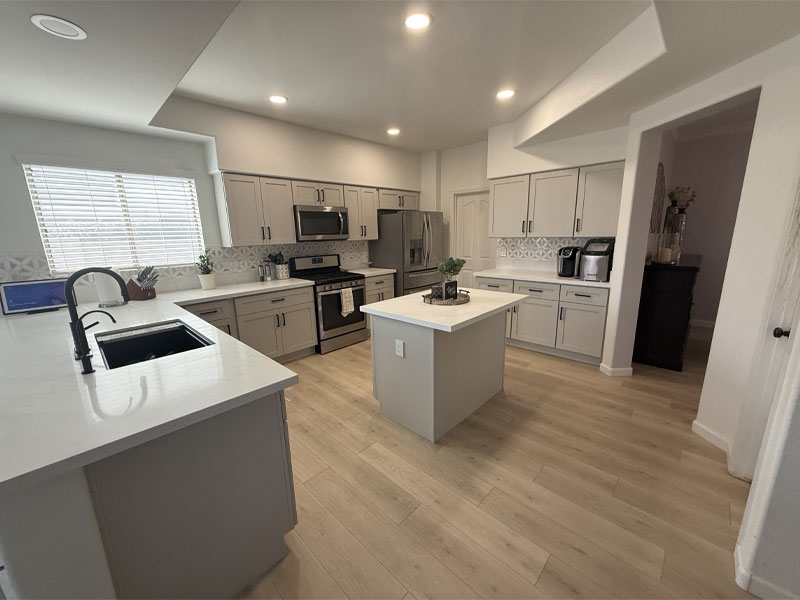 Modern kitchen design with gray cabinetry, stainless steel appliances, and a central island, showcasing a clean and functional layout ideal for restoration and reconstruction projects in Anthem, AZ.